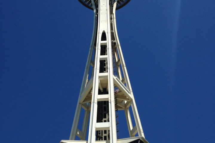 a tall clock tower sitting under a clear blue sky with Space Needle in the background